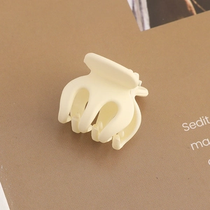 Detail shot of a cream yellow matte hair claw clip on textured background
