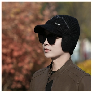 Detail of black winter knit visor hat with ear flaps and brand label on side