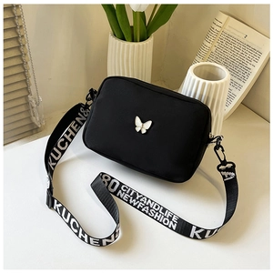 Detail of black nylon crossbody bag with butterfly motif and wide lettered strap
