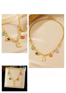 Détail du collier doré avec pendentifs papillon violet, cœur noir et pierres fines