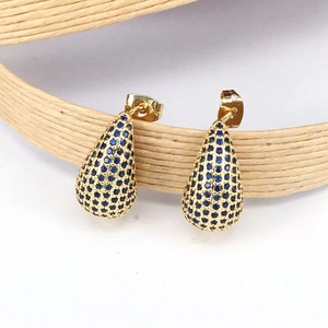 Détail macro de boucles d'oreilles goutte dorées avec cristaux bleus sur corde