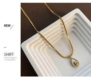 Detailed view of the gold herringbone chain necklace with shell teardrop pendant