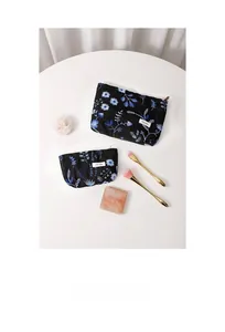 Detail of linen makeup bags with floral embroidery and golden cosmetic brushes