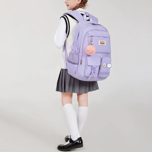 Detail of light purple school backpack with decorative badges and a pink fluffy keychain