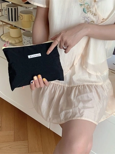 Minimalist black nylon makeup bag with brand label and colorful zipper for organizers