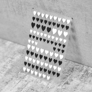 Close-up of thin black and white heart nail art stickers featuring flexible film texture