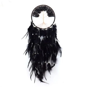 Close-up of tree of life dream catcher featuring black stones and soft hanging feathers