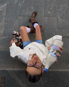 Flat lay of white half-zip sweatshirt with brown boots and glasses on stone steps