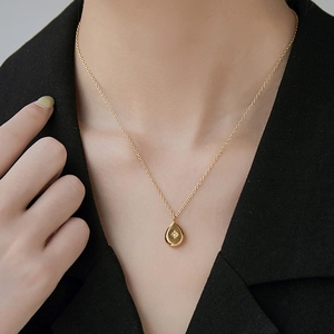 18K gold plated necklace with teardrop starburst pendant worn over black suit