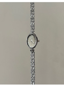 Détail du cadran ovale avec chiffres romains et bracelet à maillons métalliques