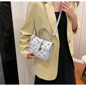 Piccola borsa quadrata argento con fiocchi neri e tracolla regolabile in foto