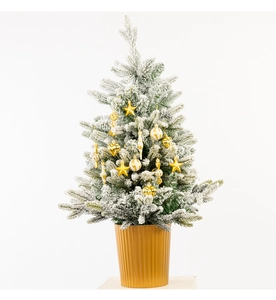 Close-up of small snow-flocked Christmas tree with gold ornaments and striped base