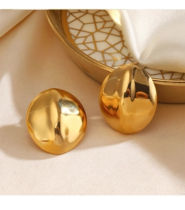 Detailed view of glossy gold circular earrings on a beige silk and gold patterned plate