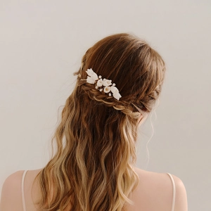 Close-up of bridal ceramic flower hair comb with white pearls on model braid