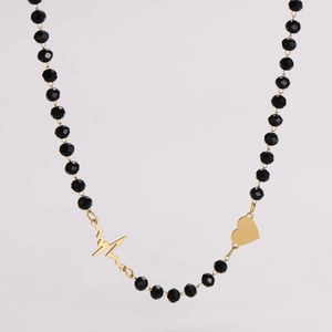 Detail of beaded necklace featuring golden heartbeat and heart shaped charm pendants