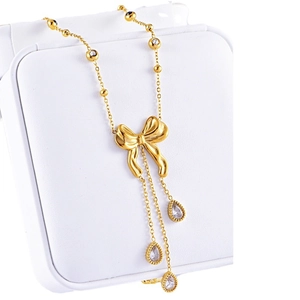 Gold bow necklace with water drop zircon tassels displayed on a white jewelry box