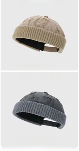 Close-up of distressed ripped knit beanie hats in beige and dark grey streetwear style