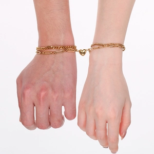 Detail of couple holding hands with magnetic heart bracelets on a white background