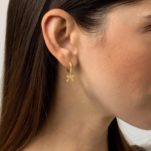 Chic gold-plated brass hoop earrings with a polished bow charm shown on a model