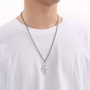 Close-up of a silver stainless steel cross pendant with twisted rope chain on a model