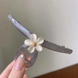 Close-up of translucent grey hair claw clip featuring a detailed cat eye stone flower