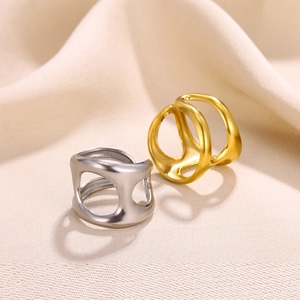 Detail of hollow geometric gold and silver rings on elegant soft fabric background