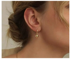 Nahaufnahme eines vergoldeten Silberohrrings mit kleiner Kugel am Modelohr