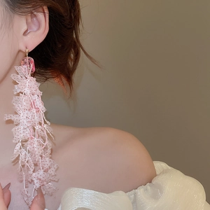 Model wearing long pink tassel earrings with transparent beads and mesh fabric layers