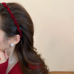 Close-up of red flocked wavy headband worn by a model with elegant pearl jewelry