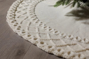 Gros plan sur la jupe de sapin de Noël tricotée crème avec motifs à losanges et bords