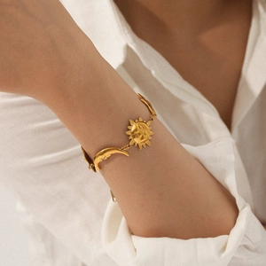 Detail shot of 18K gold plated stainless steel bracelet with sun and moon pendants