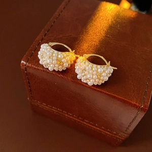 Close-up of gold-plated hoop earrings with micro-set pearls and shimmering rhinestones