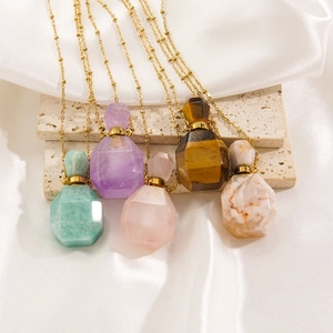Detailed macro of vintage style perfume bottle necklaces with natural gemstones and gold chain