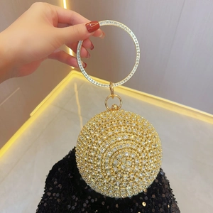Detail of a spherical gold evening bag with rhinestones and a jeweled ring handle