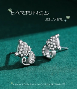 Macro shot of S925 silver cat earrings with sparkling zircon on dark green background