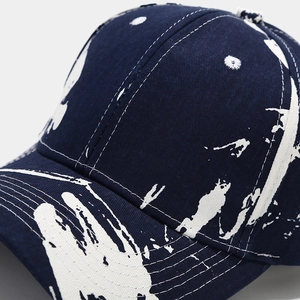 Detail of white contrast stitching and graffiti pattern on dark blue baseball cap