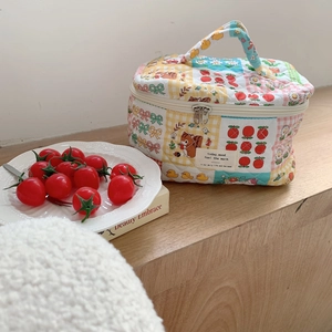Quilted floral makeup bag with top handle and colorful patchwork patterns on wood table