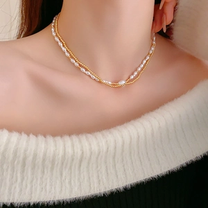 Detail view of double-layered necklace featuring white rice pearls and a fine gold chain