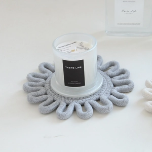 Detailed view of grey hand-woven flower-shaped cotton rope coaster on white table