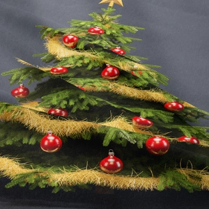 Primo piano di un albero di Natale stampato con decori rossi e oro su tessuto grigio