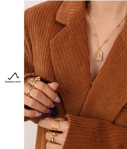 Close-up of a gold stainless steel rose pendant necklace and fashion rings on a model