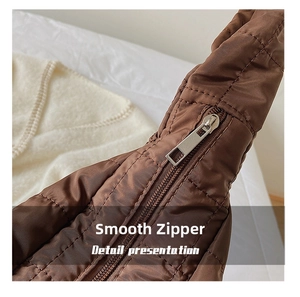 Detailed macro of smooth silver zipper on brown quilted nylon dumpling bag texture
