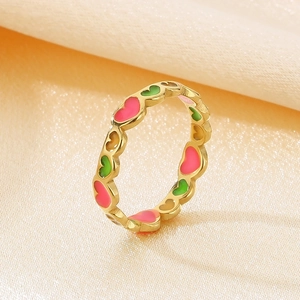 Macro shot of colorful enamel hearts on golden stainless steel ring over white silk