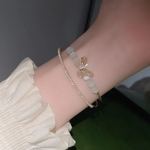 Nahaufnahme eines doppellagigen Perlenarmbands mit goldenem Schmetterling und Zirkonia