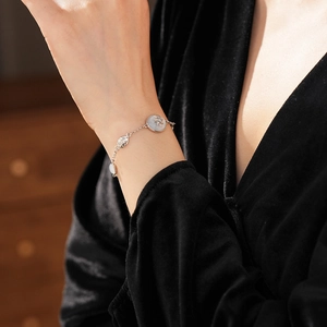 Detail of silver North Star bracelet with zircon pendant worn on a black velvet sleeve