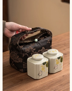 Detail of portable ceramic tea canisters with rabbit motifs and jacquard storage bag