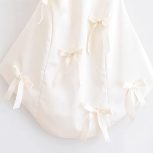 Elegant white satin top for women featuring delicate bow decorations and silky finish