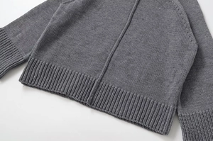 Detailed view of the dark grey knitted sweater featuring ribbed cuffs and stand collar texture