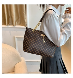 Detail of deep brown tote bag with gold geometric pattern and deer charm pendant