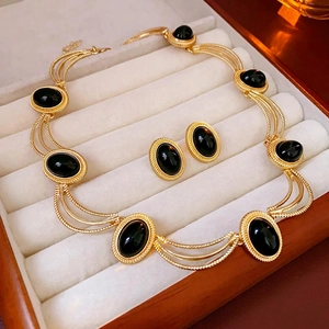 Vintage gold metal jewelry set with black oval stones including necklace and earrings